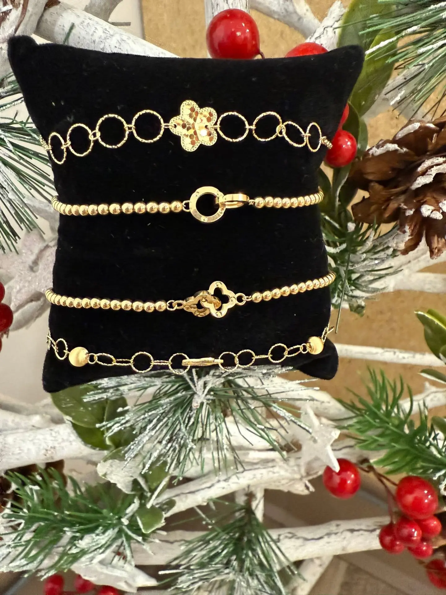 Gold beaded and clover bracelets on a velvet pillow