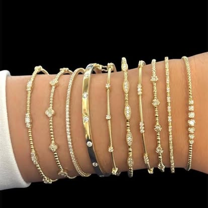 Stacked dainty gold and diamond bracelets on a wrist