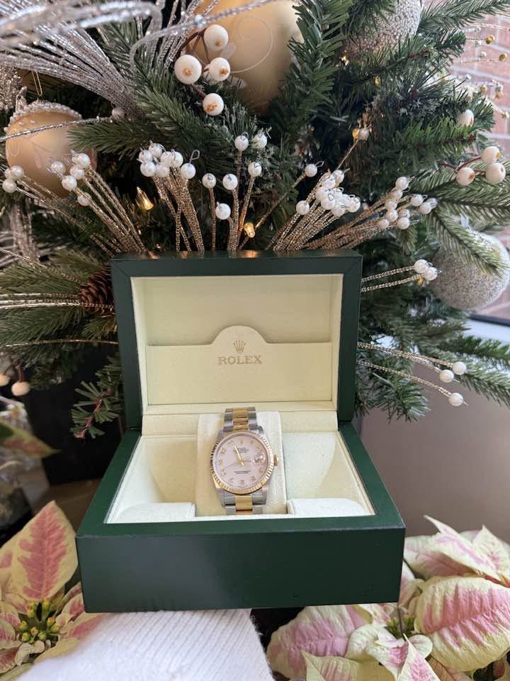Rolex Datejust in its green box in front of a holiday tree